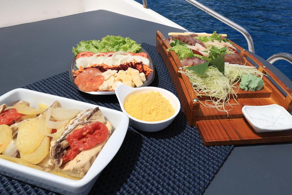 Serviço de bordo com peixe na brasa, sashimi e saladas no passeio de lancha em Fernando de Noronha